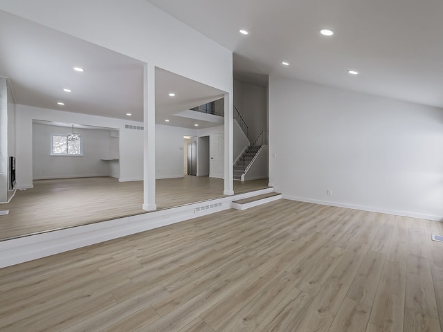 basement featuring stairway, light wood-type flooring, and visible vents