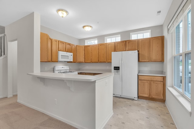 kitchen with white appliances, kitchen peninsula, and a breakfast bar