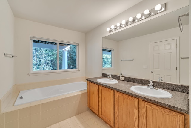 bathroom featuring tile patterned floors, vanity, and tiled bath