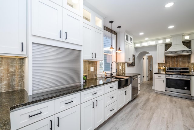 6735 S Scottdale Rd, Berrien Springs, MI 49103 - kitchen with arched walkways, custom range hood, appliances with stainless steel finishes, white cabinets, and a sink