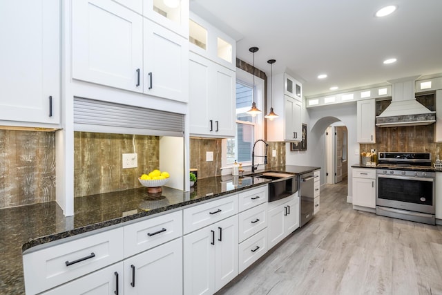 6735 S Scottdale Rd, Berrien Springs, MI 49103 - kitchen featuring arched walkways, custom range hood, stainless steel appliances, white cabinetry, and a sink