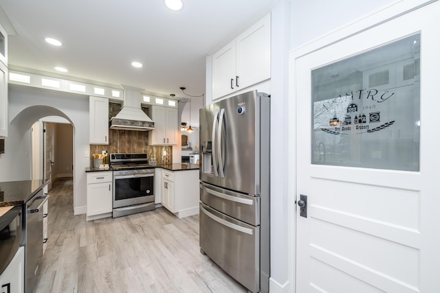 6735 S Scottdale Rd, Berrien Springs, MI 49103 - kitchen featuring arched walkways, stainless steel appliances, premium range hood, light wood-style floors, and tasteful backsplash