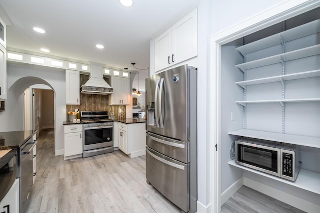 6735 S Scottdale Rd, Berrien Springs, MI 49103 - kitchen featuring arched walkways, decorative backsplash, appliances with stainless steel finishes, premium range hood, and white cabinetry