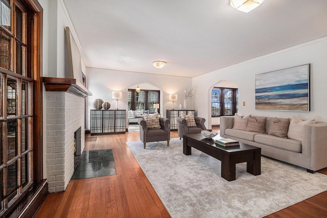 living room with hardwood / wood-style floors, a wealth of natural light, and a brick fireplace