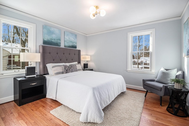 bedroom featuring multiple windows, ornamental molding, and light hardwood / wood-style flooring