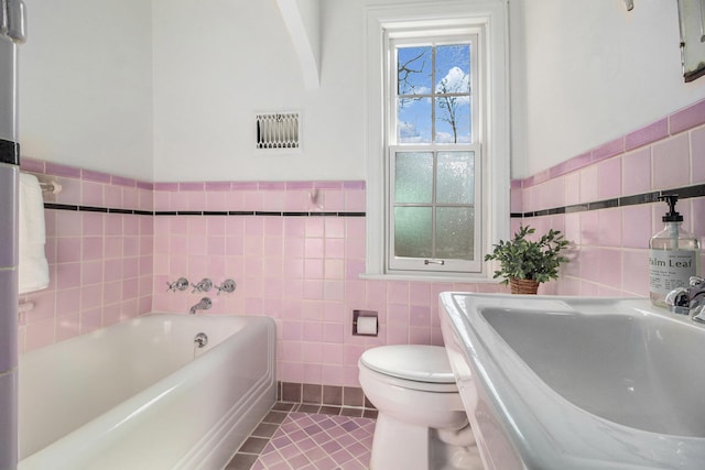 bathroom with tile patterned floors, toilet, sink, tile walls, and a bathtub