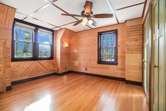 unfurnished room featuring ceiling fan, light hardwood / wood-style flooring, and wood walls