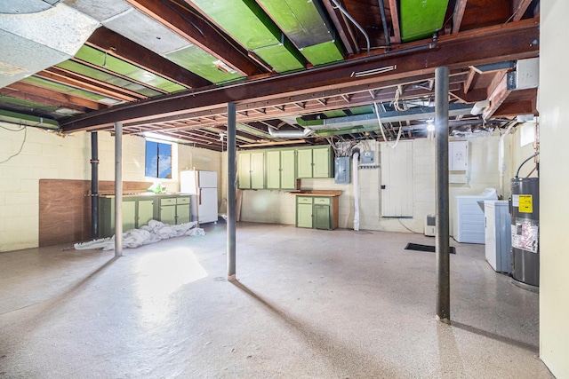 basement with white refrigerator, electric panel, independent washer and dryer, and water heater