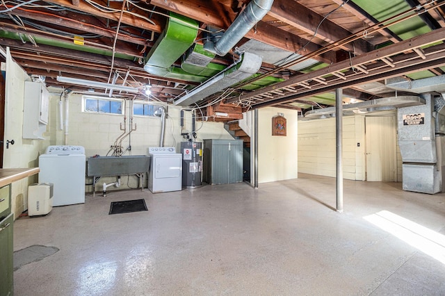 basement featuring heating unit, sink, washer and clothes dryer, and electric water heater