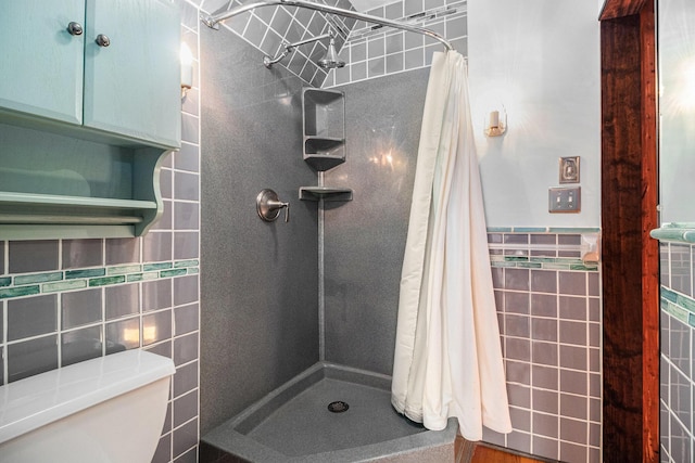 bathroom featuring toilet, a shower with shower curtain, and tile walls