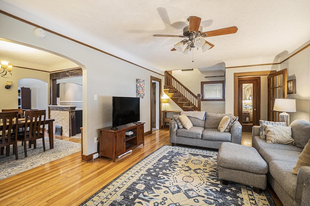 living room with hardwood / wood-style flooring, crown molding, ceiling fan with notable chandelier, and a textured ceiling