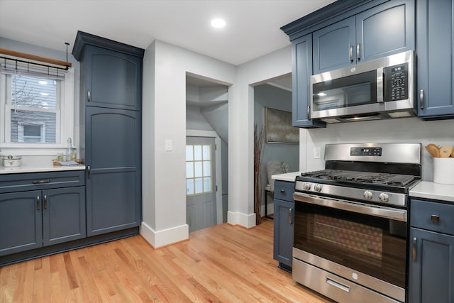 kitchen featuring blue cabinets, light hardwood / wood-style floors, and appliances with stainless steel finishes