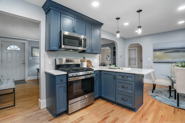 kitchen featuring hanging light fixtures, appliances with stainless steel finishes, blue cabinets, and kitchen peninsula