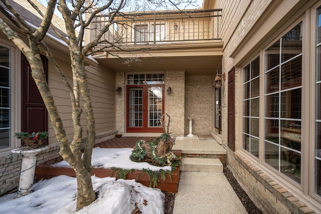 doorway to property with a balcony, covered porch, and brick siding