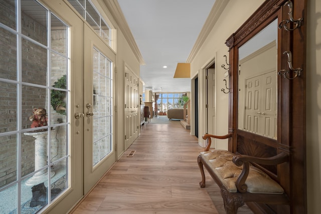 hall featuring french doors, light wood-style flooring, and crown molding