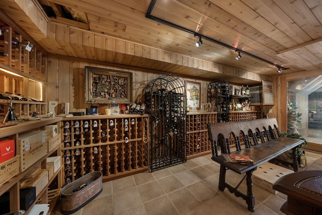 wine area featuring wood ceiling, wood walls, and track lighting