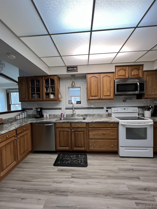 kitchen with sink, backsplash, stainless steel appliances, light hardwood / wood-style floors, and a drop ceiling