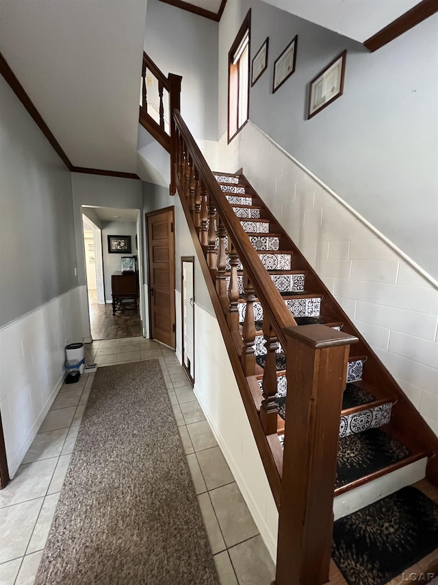 stairs with crown molding and tile patterned floors