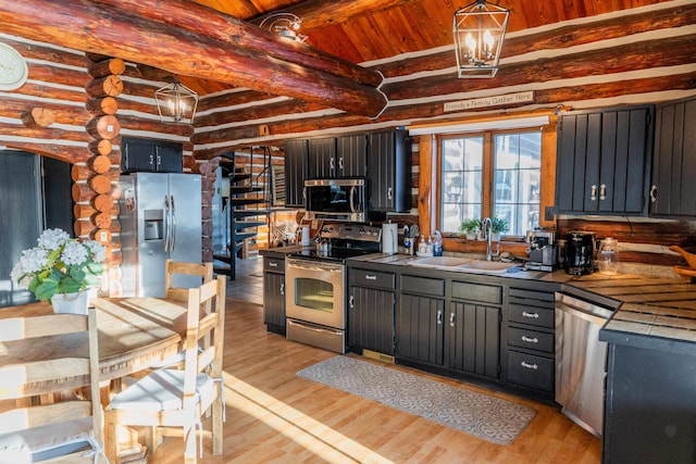 kitchen with beam ceiling, appliances with stainless steel finishes, sink, and light wood-type flooring