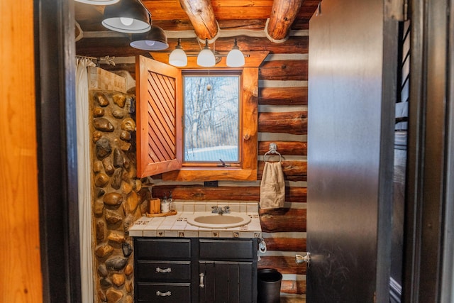 bathroom with beamed ceiling, vanity, and rustic walls