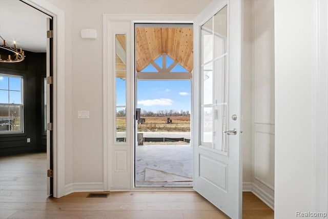 doorway featuring a chandelier and light hardwood / wood-style floors