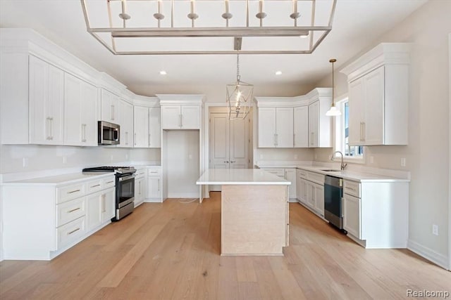 kitchen with pendant lighting, stainless steel appliances, a center island, and white cabinets