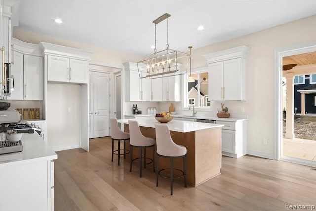 kitchen featuring white cabinetry, light hardwood / wood-style floors, hanging light fixtures, and a kitchen island