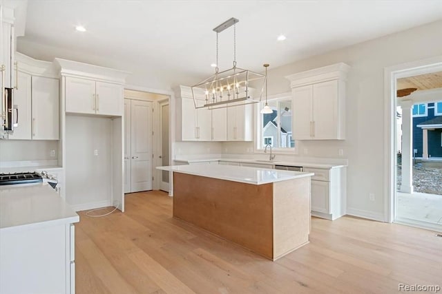 kitchen featuring sink, hanging light fixtures, a center island, light hardwood / wood-style floors, and white cabinets