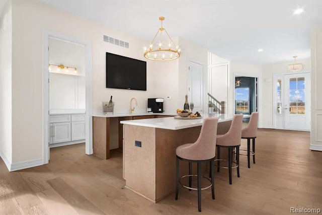 kitchen with white cabinetry, hanging light fixtures, light hardwood / wood-style flooring, and a kitchen island