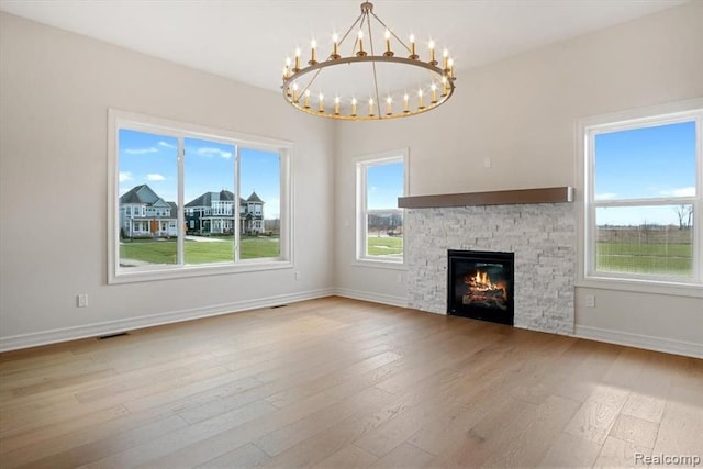 unfurnished living room with a notable chandelier, a fireplace, and light hardwood / wood-style flooring