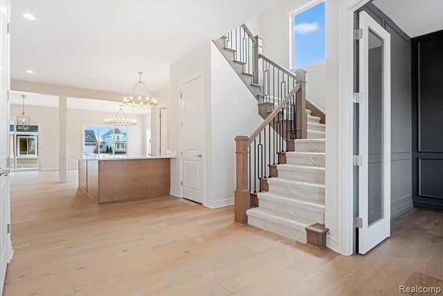 stairway with an inviting chandelier and wood-type flooring