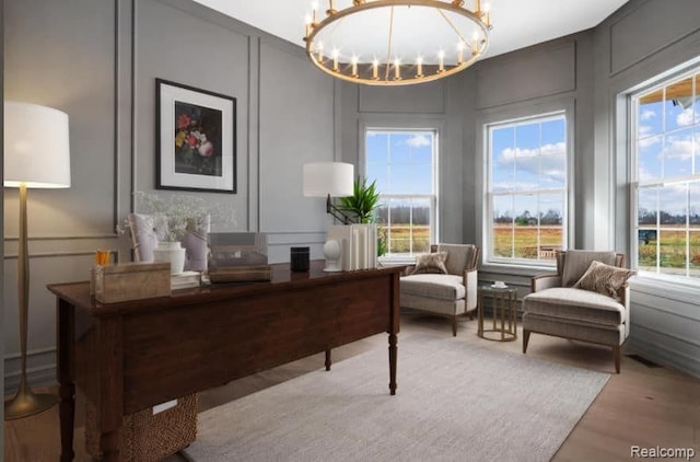 home office with an inviting chandelier and light hardwood / wood-style flooring