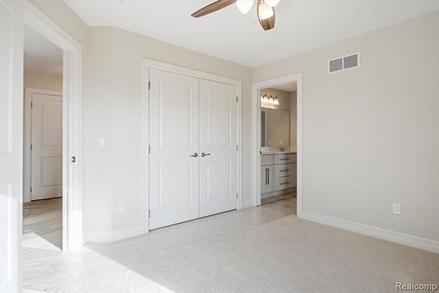 unfurnished bedroom featuring ceiling fan, ensuite bathroom, and a closet