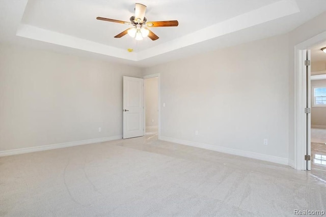 spare room featuring ceiling fan, a raised ceiling, and light carpet