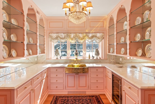 kitchen featuring decorative light fixtures, light hardwood / wood-style floors, sink, beverage cooler, and a chandelier