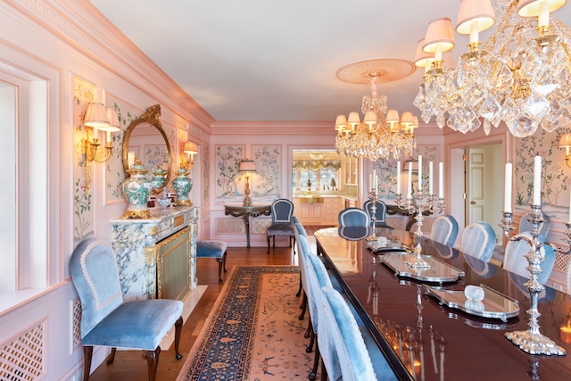 dining area with hardwood / wood-style flooring, ornamental molding, and a chandelier