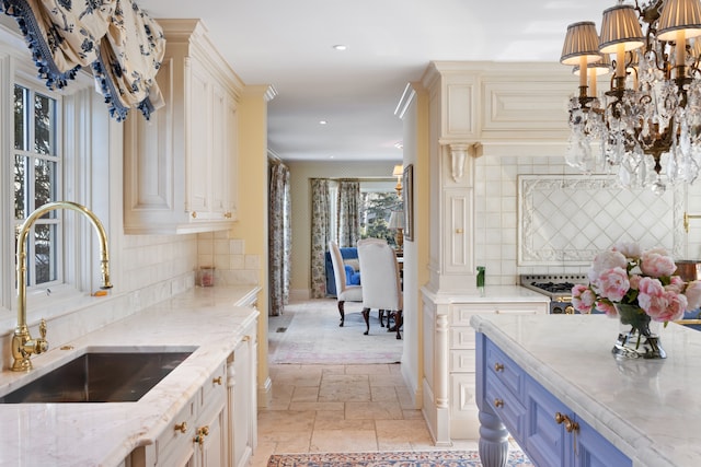 kitchen featuring a chandelier, sink, decorative light fixtures, light stone countertops, and decorative backsplash