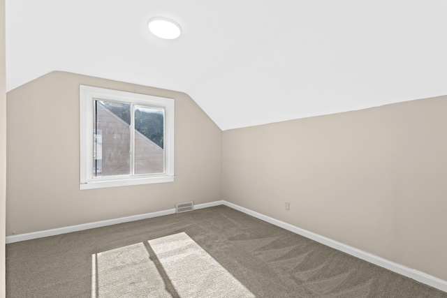 additional living space featuring lofted ceiling and dark colored carpet