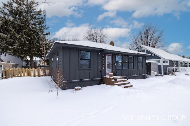 view of front of house featuring a chimney, fence, and board and batten siding