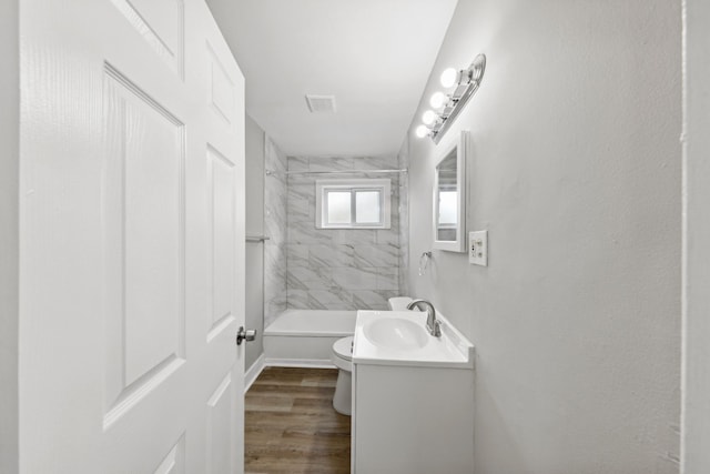 full bathroom featuring vanity, hardwood / wood-style floors, tiled shower / bath combo, and toilet