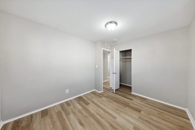 unfurnished bedroom featuring light hardwood / wood-style flooring and a closet