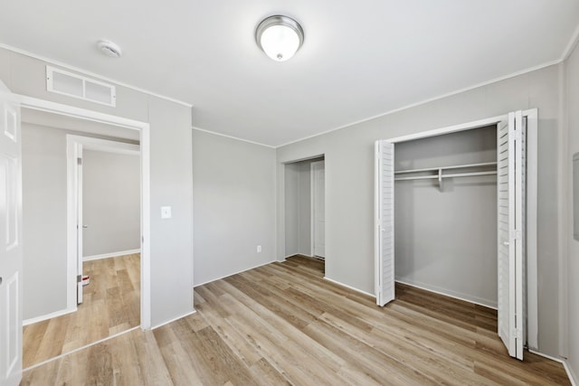 unfurnished bedroom with crown molding, two closets, and light hardwood / wood-style floors