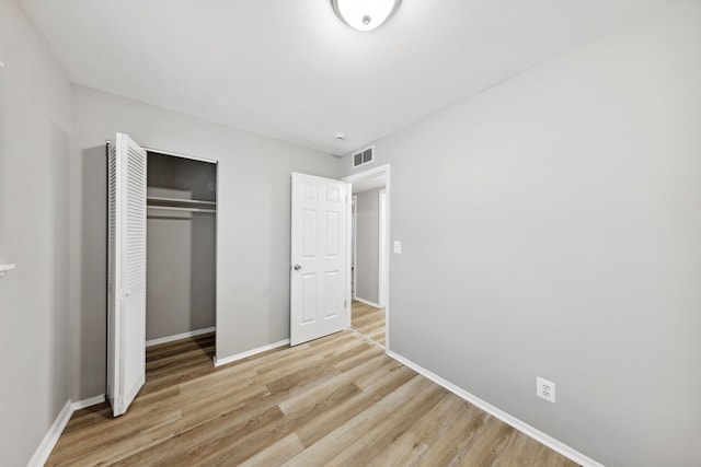 unfurnished bedroom with light wood-type flooring and a closet