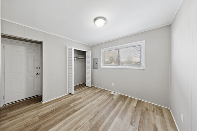 unfurnished bedroom with a closet, electric panel, and light hardwood / wood-style flooring