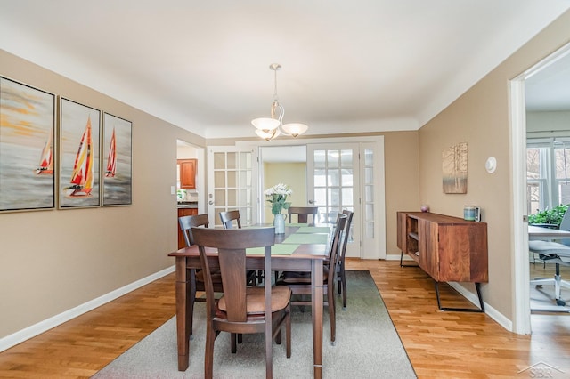 dining space with light hardwood / wood-style flooring and a chandelier