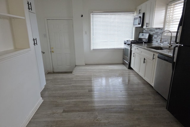 30052 Schoenherr Rd, Warren, MI 48088 - kitchen with a sink, stainless steel appliances, light wood-style flooring, backsplash, and white cabinetry