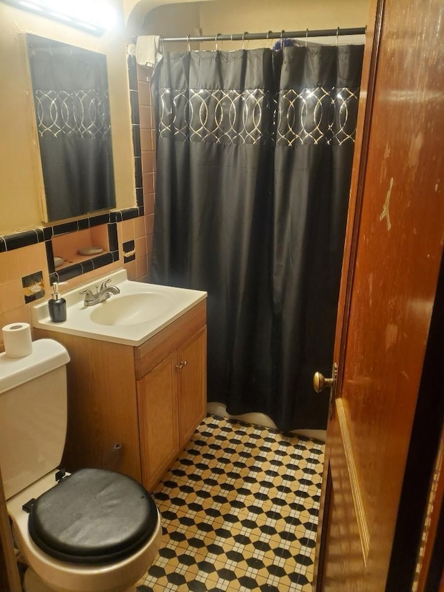 bathroom with vanity, toilet, and tile walls