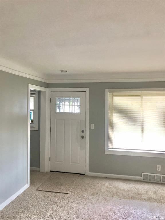 carpeted entrance foyer with crown molding