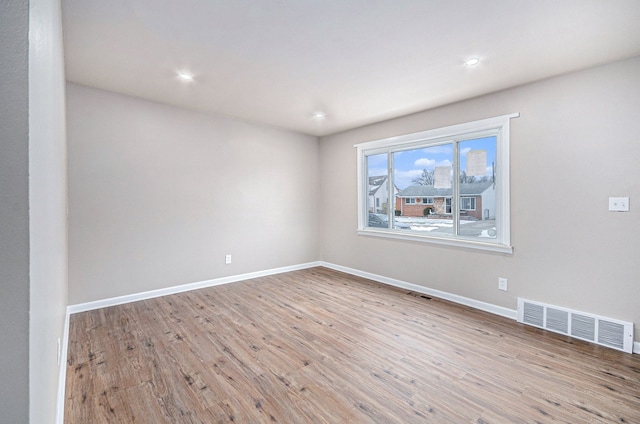 unfurnished room with visible vents, baseboards, and wood finished floors