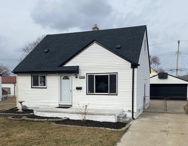 view of front of home featuring a shingled roof, a chimney, a detached garage, a gate, and fence